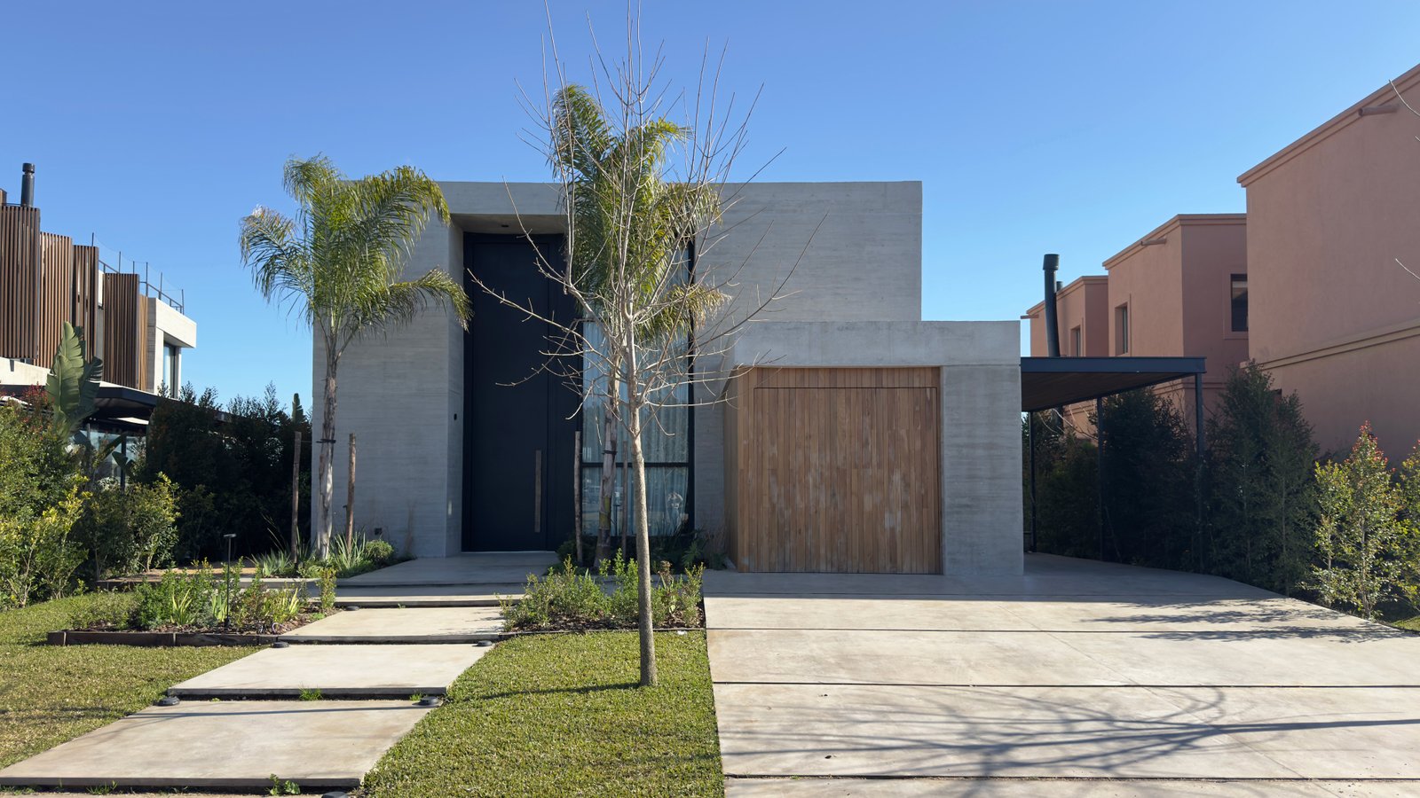 Casa moderna con fachada de hormigón y madera, entrada y garaje integrados — proyecto CASA MHN, por Hermann Arquitectos, en Nordelta